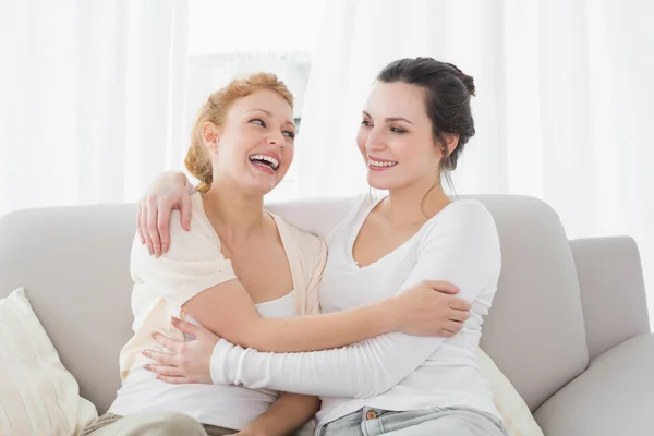 Glada väninnor embracing i vardagsrum — Stockfoto