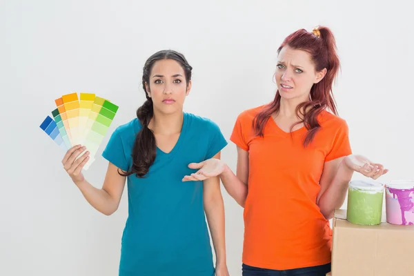 Amigos confusos eligiendo el color para pintar una habitación — Foto de Stock