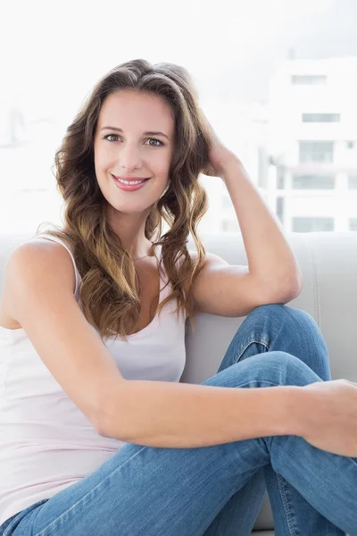 Retrato de uma mulher sorridente sentada no sofá — Fotografia de Stock