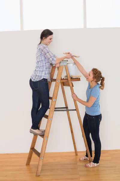 Dos amigas con escalera en una casa nueva — Foto de Stock
