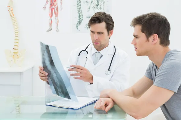 Male doctor explaining spine x-ray to patient