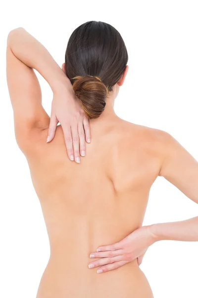 Rear view of a fit topless young woman with back pain — Stock Photo, Image