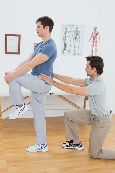 Vista lateral de un fisioterapeuta masculino examinando mans espalda —  Fotos de Stock