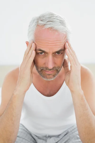 Зрелый мужчина страдает от головной боли в постели — стоковое фото