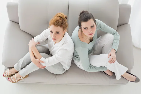 Amigos femeninos infelices que no hablan después de discutir en el sofá —  Fotos de Stock