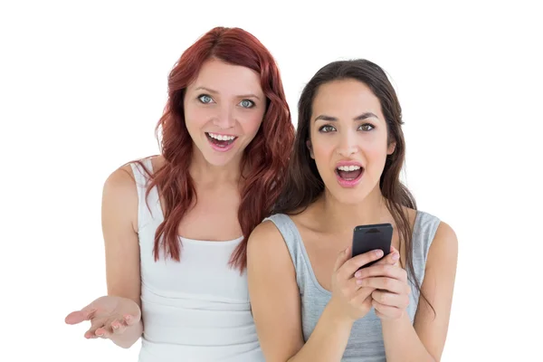 Shocked casual young female friends with mobile phone — Stock Photo, Image