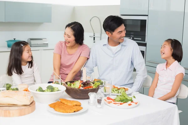 Familia alegre de cuatro personas disfrutando de una comida saludable en la cocina —  Fotos de Stock