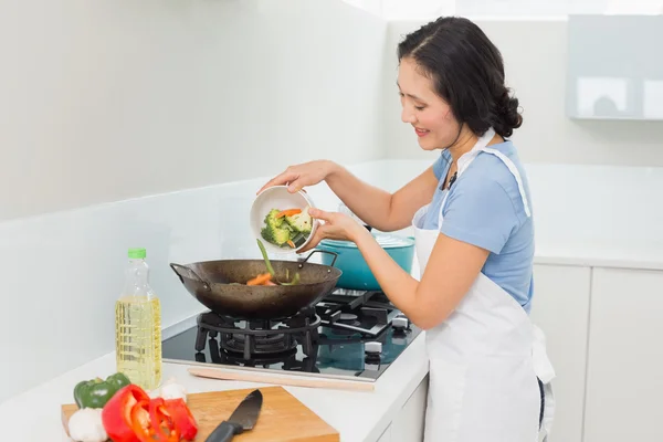 Smiling young woman preparing food in kitchen — Stock Photo, Image