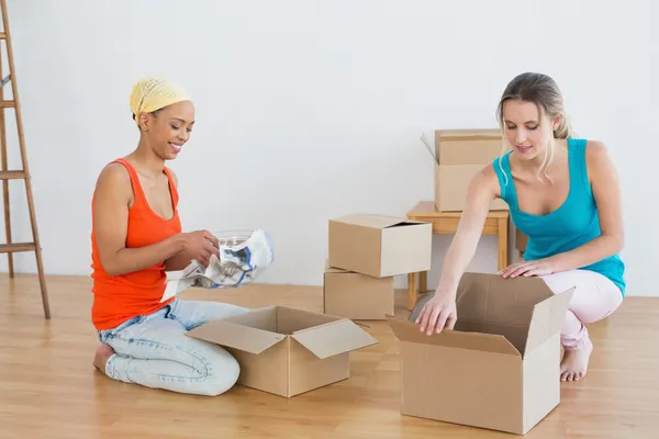 Happy friends unwrapping boxes in a new house — Stock Photo, Image