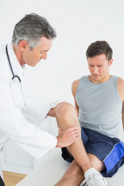 Dispiaciuto giovane uomo ottenere la sua gamba esaminata — Foto Stock
