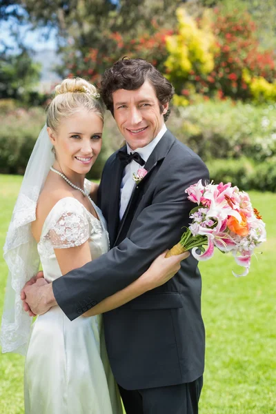 Sposa e sposo abbracciando e sorridendo alla macchina fotografica — Foto Stock