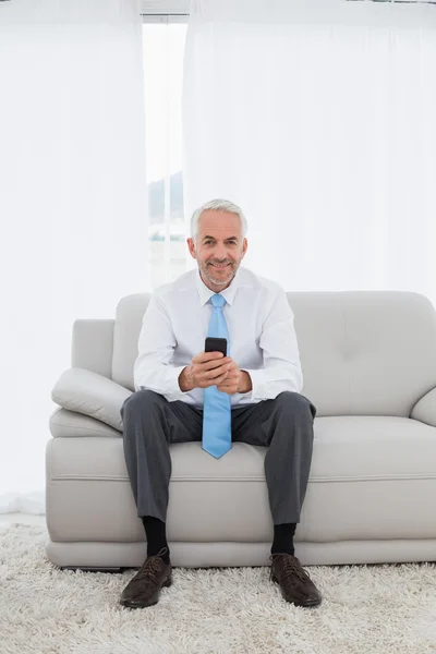 Elegant mature businessman text messaging at home — Stock Photo, Image