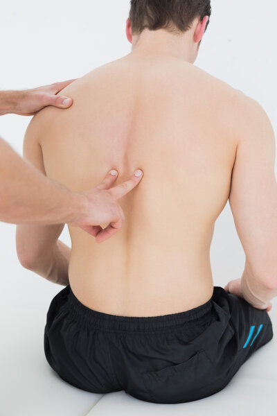 Rear view of a man being massaged by a physiotherapist