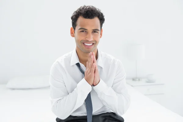 Portrait of a smiling businessman sitting on bed — Stock Photo, Image