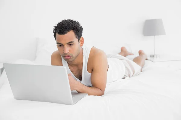 Casual man met laptop in bed — Stockfoto