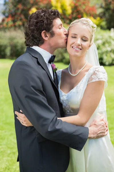 Noivo beijando sua bela nova esposa na bochecha — Fotografia de Stock