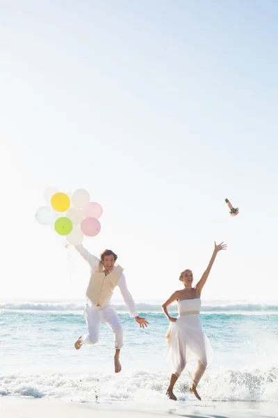 Groom holding balloons and bride throwing her bouquet jumping — Stock Photo, Image
