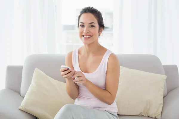 Портрет улыбающейся женщины, отправляющей смс на диване — стоковое фото