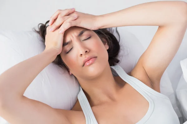 Mujer somnolienta con dolor de cabeza en la cama —  Fotos de Stock