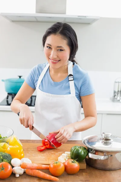 Lachende vrouw hakken groenten in de keuken — Stockfoto