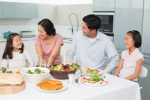 Family of four enjoying healthy meal in kitchen — Stock Photo, Image