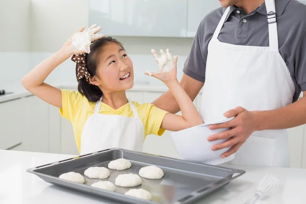 Menina alegre com seu pai preparando biscoitos na cozinha — Fotografia de Stock