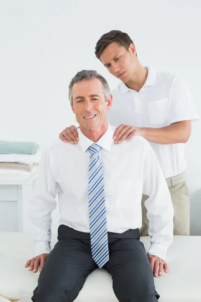 Quiroprático massageando um ombro de pacientes maduros — Fotografia de Stock