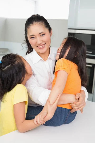 Lachende moeder met haar jonge dochters in keuken — Stockfoto