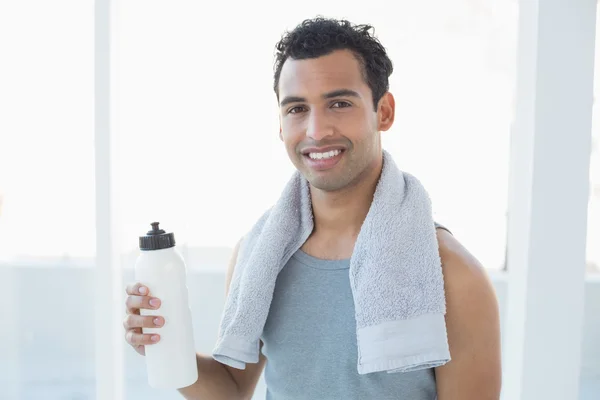 Mann mit Handtuch um den Hals hält Wasserflasche im Fitnessstudio — Stockfoto