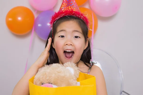 Shocked little girl with gift at her birthday party — Stock Photo, Image