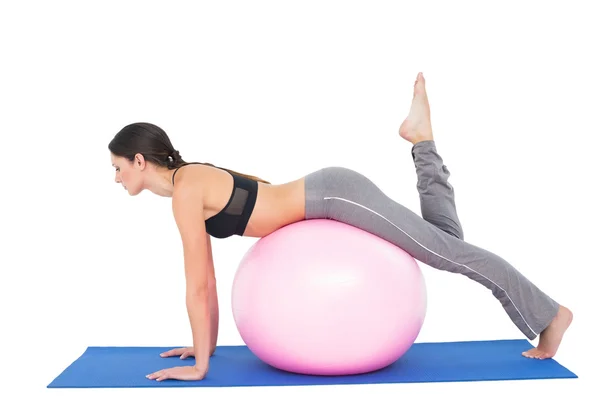 Vista lateral de uma mulher apta a se esticar na bola de fitness — Fotografia de Stock