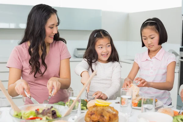 Mujer con dos niñas teniendo comida en la cocina — Foto de Stock