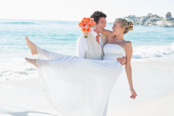 Riendo novio llevando a su hermosa esposa rubia sonriendo a la cámara — Foto de Stock