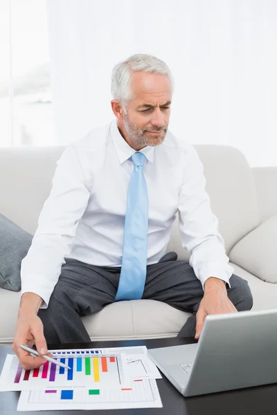 Affärsman som arbetar på grafer och laptop hemma — Stockfoto