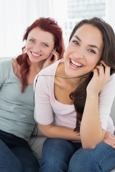 Cheerful friends listening music through earphones together — Stock Photo, Image
