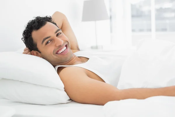 Fröhlicher junger Mann ruht sich im Bett aus — Stockfoto