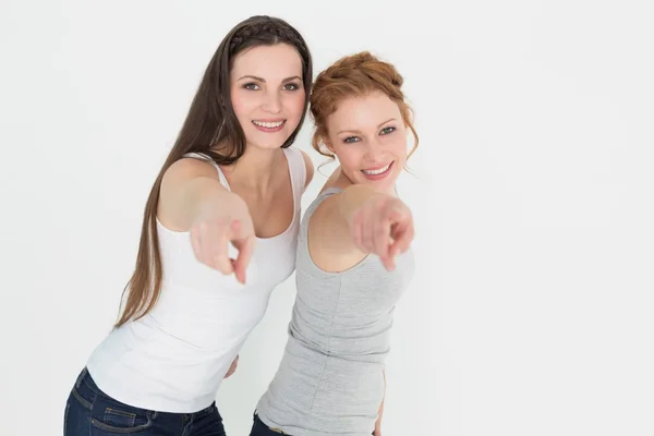 Vrouwelijke vrienden wijzen tegen witte achtergrond — Stockfoto