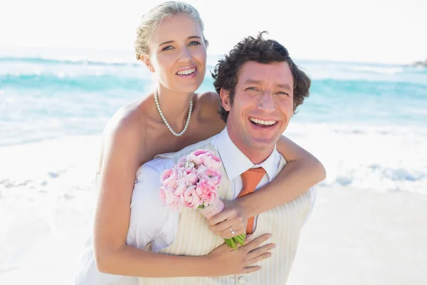 Handsome groom giving his new wife a piggy back — Stock Photo, Image