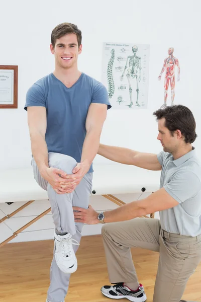 Terapeuta masculino assistindo homem com exercícios de alongamento — Fotografia de Stock