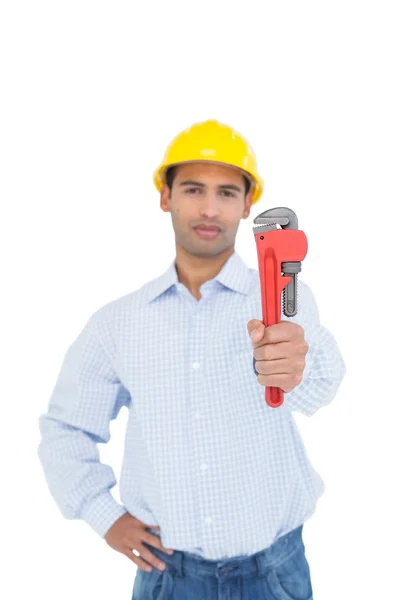 Schöner junger Handwerker, der einen Rohrschlüssel hinhält — Stockfoto