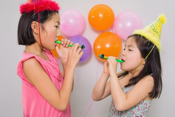 Girls blowing noisemakers at a birthday party — Stock Photo, Image