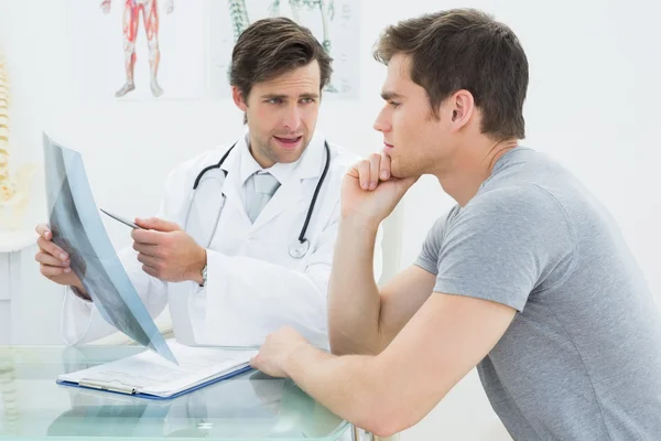 Male doctor explaining spine x-ray to patient — Stockfoto