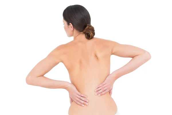 Rear view of a fit topless young woman with back pain — Stock Photo, Image