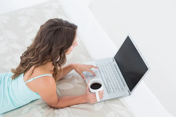 Mujer usando portátil con taza de café en la cama — Foto de Stock