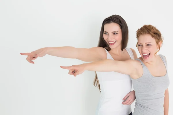 Happy friends pointing away against white background — Stock Photo, Image