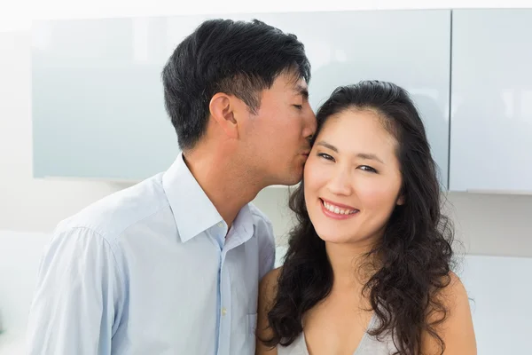 Nahaufnahme eines jungen Mannes, der eine Frau in der Küche küsst — Stockfoto