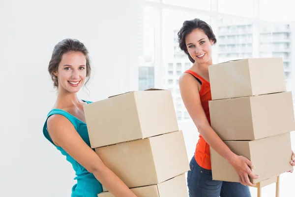 Mujeres amigas llevando cajas en casa nueva —  Fotos de Stock