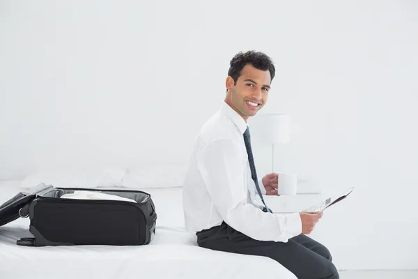 Biznesmen z filiżanki i gazety przez bagaż w pokoju hotelowym — Zdjęcie stockowe