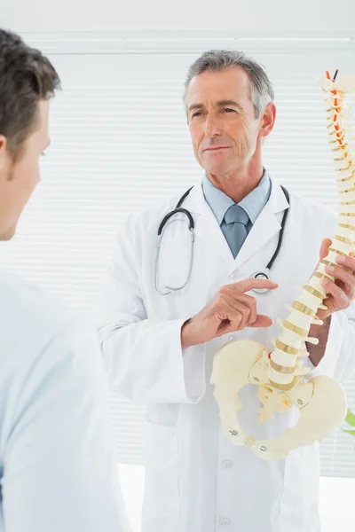 Médico explicando a coluna vertebral ao paciente no consultório — Fotografia de Stock