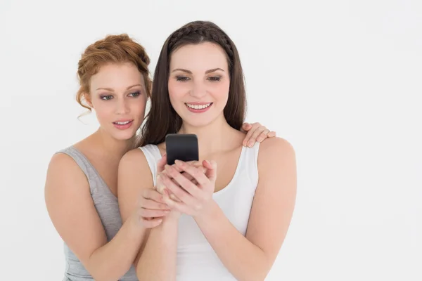 Lässige junge Freundinnen, die aufs Handy schauen — Stockfoto